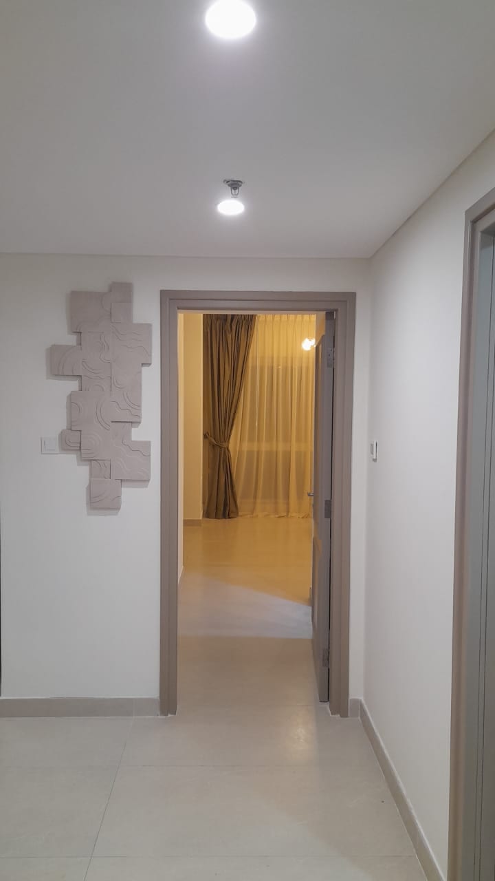 Apartment hallway with a textured wall panel, opening into a bedroom with drawn curtains