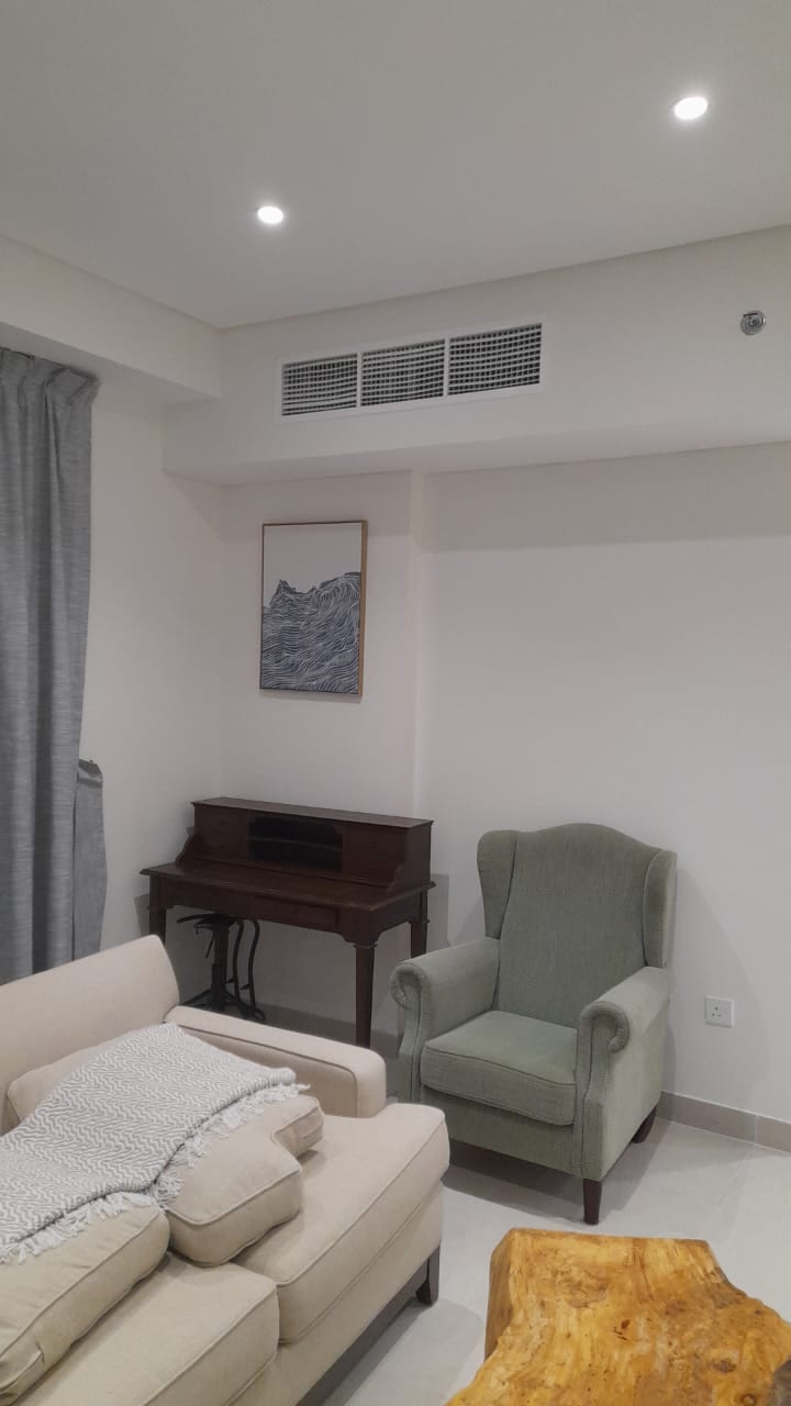 Apartment living room with a cream sofa, a green armchair and a wooden writing desk